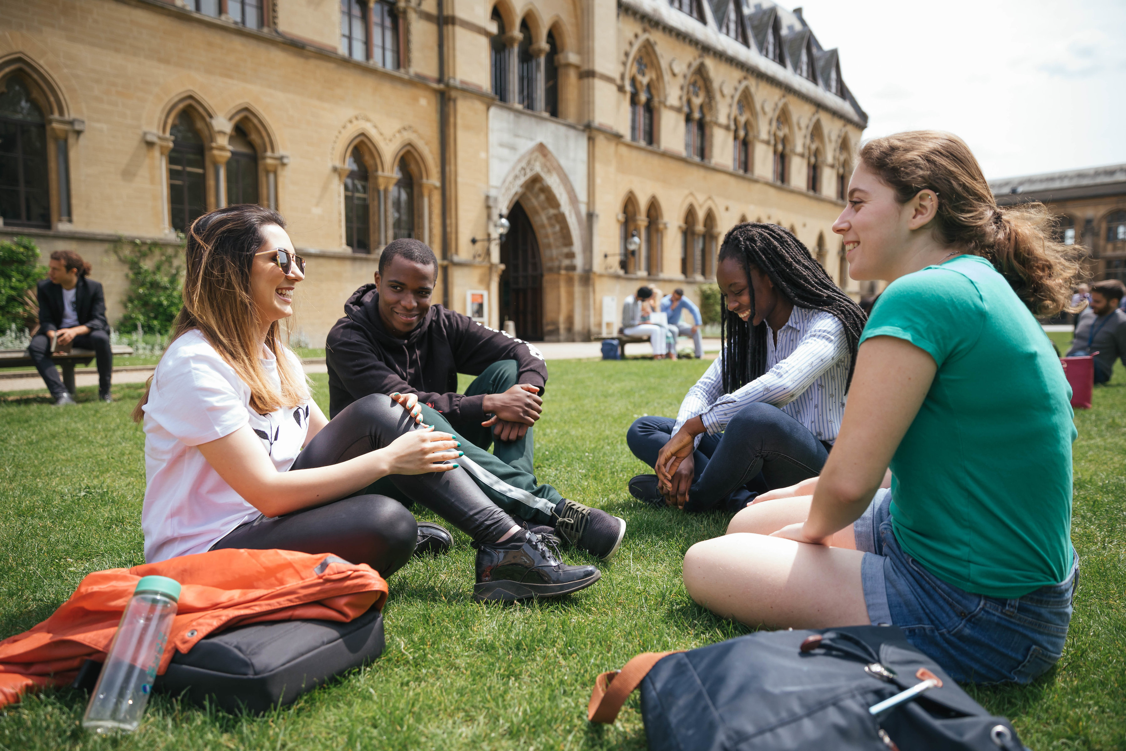 Four students sat chatting on the grass outside the Oxford Museum of Natural History 