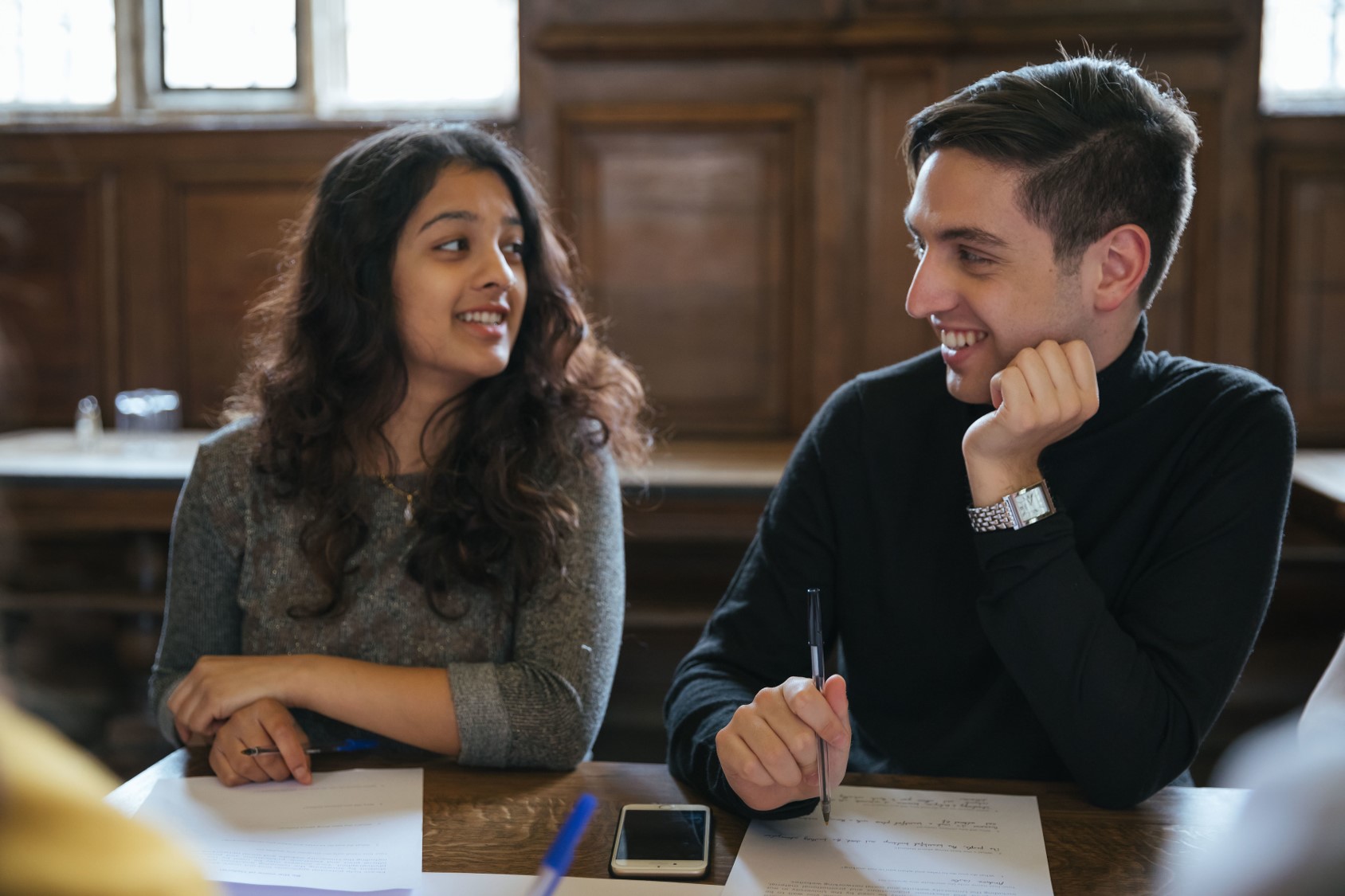 Two students chatting while working in a college dining hall