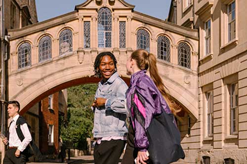 Two students walking in front of Herford college and the Bridge of Sighs