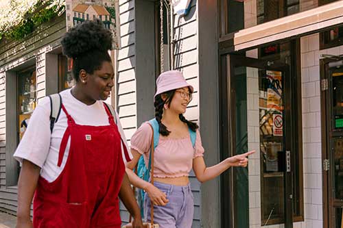 Two students walking in front of restaurant doors