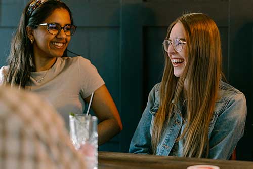 Two students laughing at a restaurant table