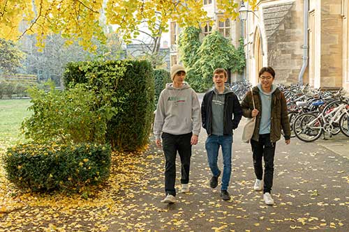 Three students walking through college in autumn
