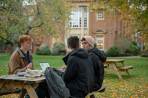 Three students studying at a picnic table in college