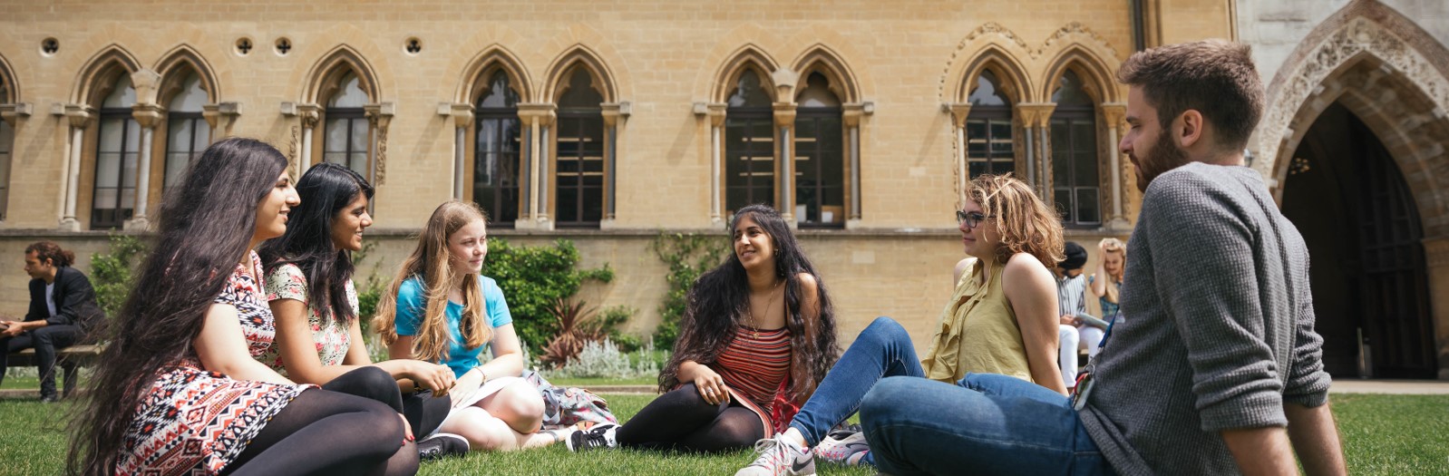 A group of student relax on the grass outside the Natural History Museum