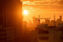 Mumbai, India - September 2022: Silhouette of a construction crane on a building at sunset with a skyline of the suburb of Kandivali in the background. Credit: Balaji Srinivasan