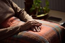 Old woman sitting in armchair with legs covered by a blanket. Credit: izusek, Getty Images.
