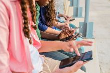 Teens use mobile phones outside. Credit: FG Trade Latin, Getty Images