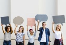 A mixed group of five students holding cut out speech bubbles