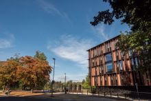 Photo of outside of Beecroft building against bright blue sky with autumn-coloured trees in backgrouns