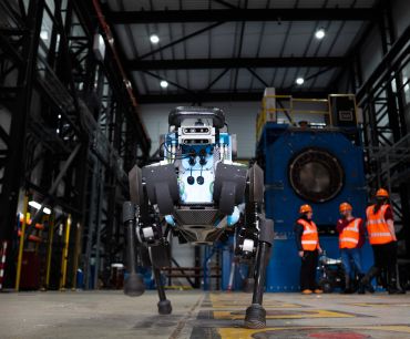 Autonomous robot in a warehouse with three people in hard hats and hi-vis vests