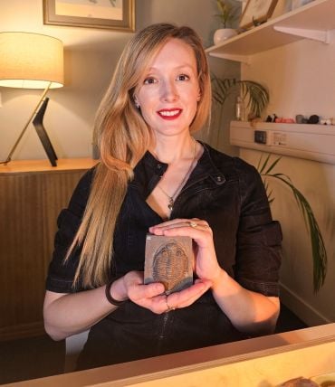 Professor Erin Saupe - a white lady with long blonde hair - holds a fossil trilobite in an office.