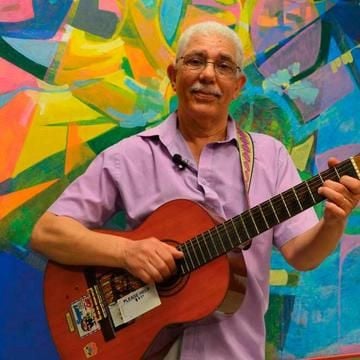 Image of musician Alexander D. Great holding an acoustic guitar in front of a colourfully painted background
