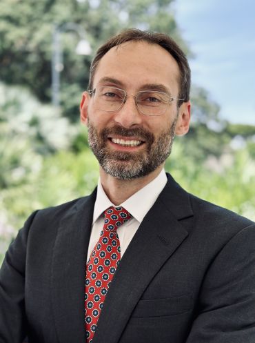Michael Bronstein, a middle-aged white man wearing a suit and tie, and glasses