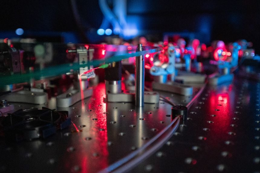 Close up shot of scientific apparatus with lenses attached to a board to guide lasers.