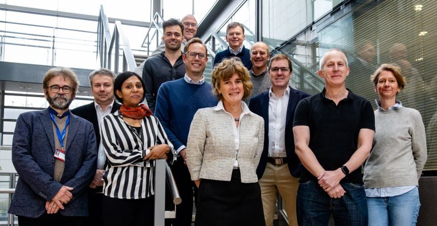 A diverse group of men and women standing on a staircase indoors.