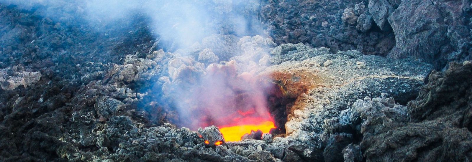 A smouldering, volcanic hole, with lava flowing inside it.