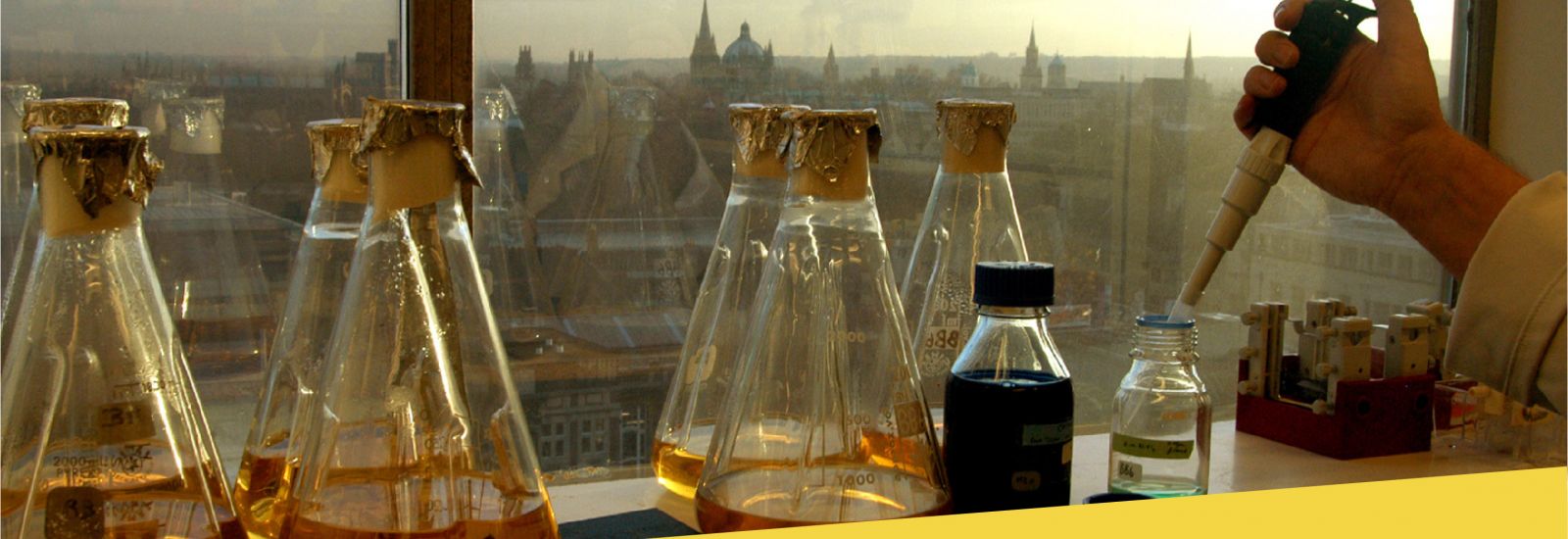 Conical flasks in a Chemistry lab in front of a window overlooking Oxford city centre
