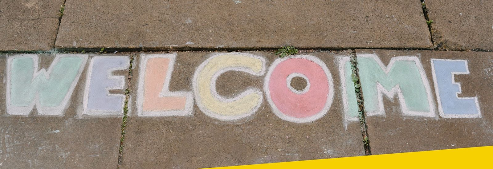 The word 'welcome' chalked on pavement