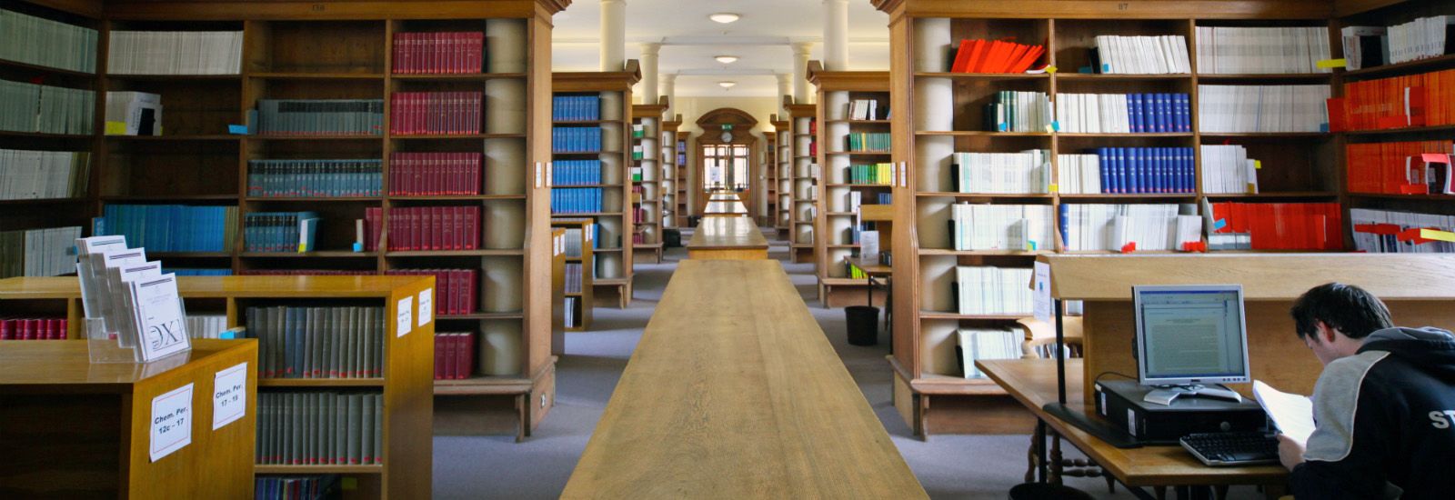 Bookcases and a student working in a library
