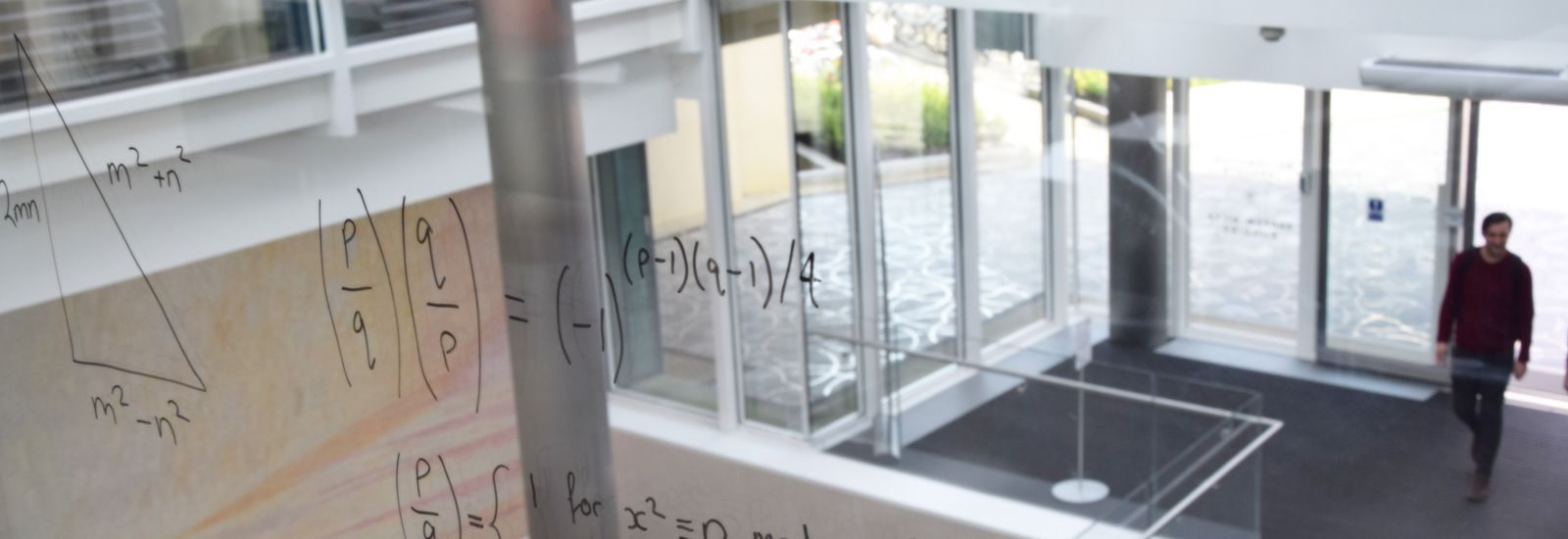 Equations written on glass looking over the entrance to the Mathematical Institute
