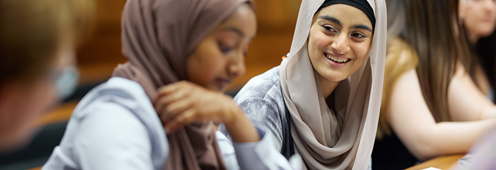 Two female students in an education setting, smiling together