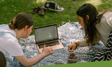 Photo of two students with a laptop outside