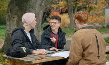 Three students studying at a picnic table