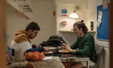 Two students sharing a meal in a college kitchen