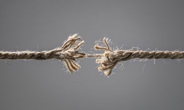 A frayed rope being held together by a single thread