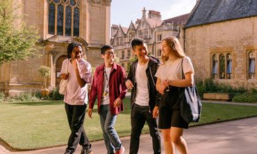 Four students walking through a college courtyard