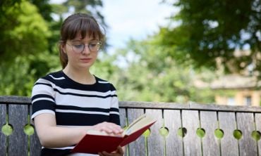 A student sat on a bench reading a book