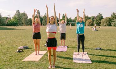 Students practising yoga outside in a park