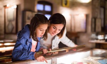 Mother and daughter looking at exhibition in glass display case in a museum