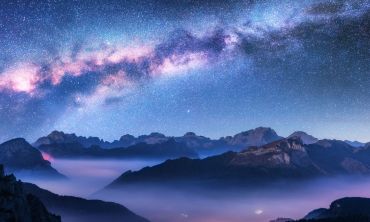 Milky Way above mountains in fog at night in autumn