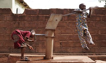 Boy Pumping Water For His Sister