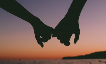 Holding hands in front of beach sunset