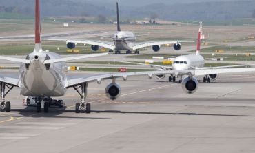 Three commercial passenger jets on an airport runway. wo moving away, one approaching. It looks like the aircrafts are deadlocked in a taxiway traffic jam.