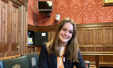 Chloe Pomfret sits at a desk in a room in the House of Commons