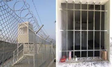 Left: A watch tower overlooking a barbed wire fence. Right: Looking inward through a barred window into a cell. A bed is visible and a door in the far wall.