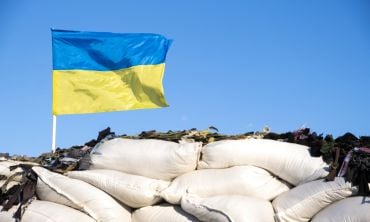 Ukrainian flag blue yellow color flutters in blue sky on barricades. Ukraine Russia War 2022. Credit: Nemer-T, Getty Images