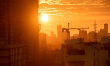 Mumbai, India - September 2022: Silhouette of a construction crane on a building at sunset with a skyline of the suburb of Kandivali in the background. Credit: Balaji Srinivasan