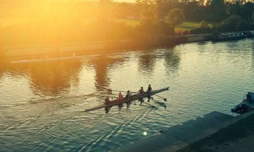 Students rowing up the river at sunset