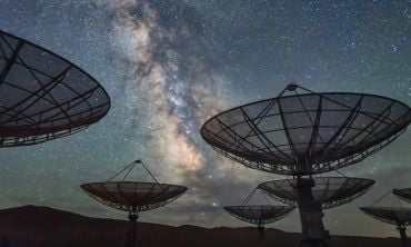A radio telescope observatory under a starry night sky.