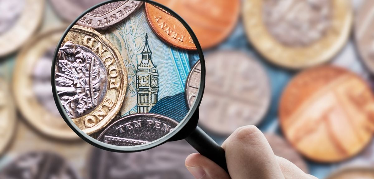 Magnifying glass over Big Ben surrounded by British currency