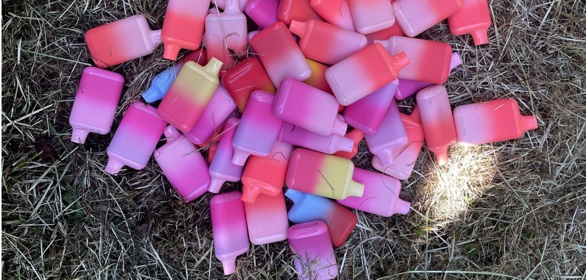 A pile of disposable e-cigarettes on the ground.