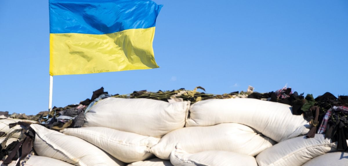 Ukrainian flag blue yellow color flutters in blue sky on barricades. Ukraine Russia War 2022. Credit: Nemer-T, Getty Images