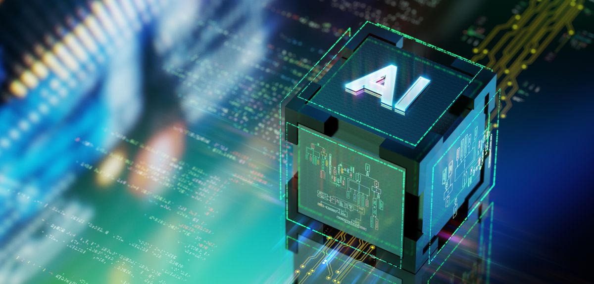Abstract image showing a 3D cube with the word ‘AI’ against a background of computer code and computer chip designs. 