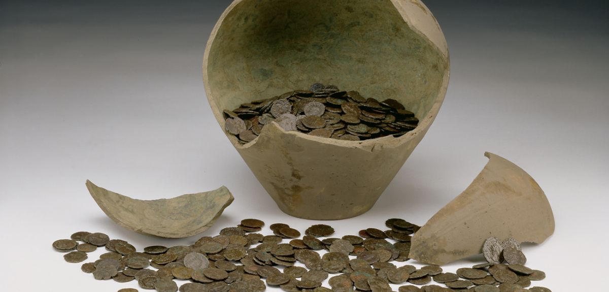 A broken pot with a coin hoard spilling out