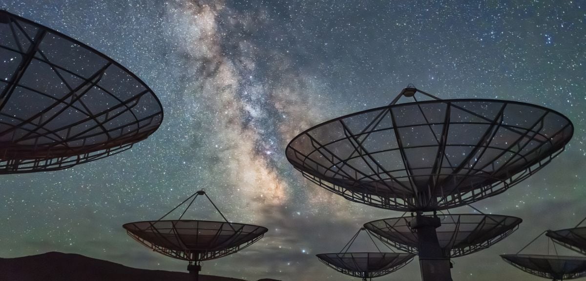 A radio telescope observatory under a starry night sky.