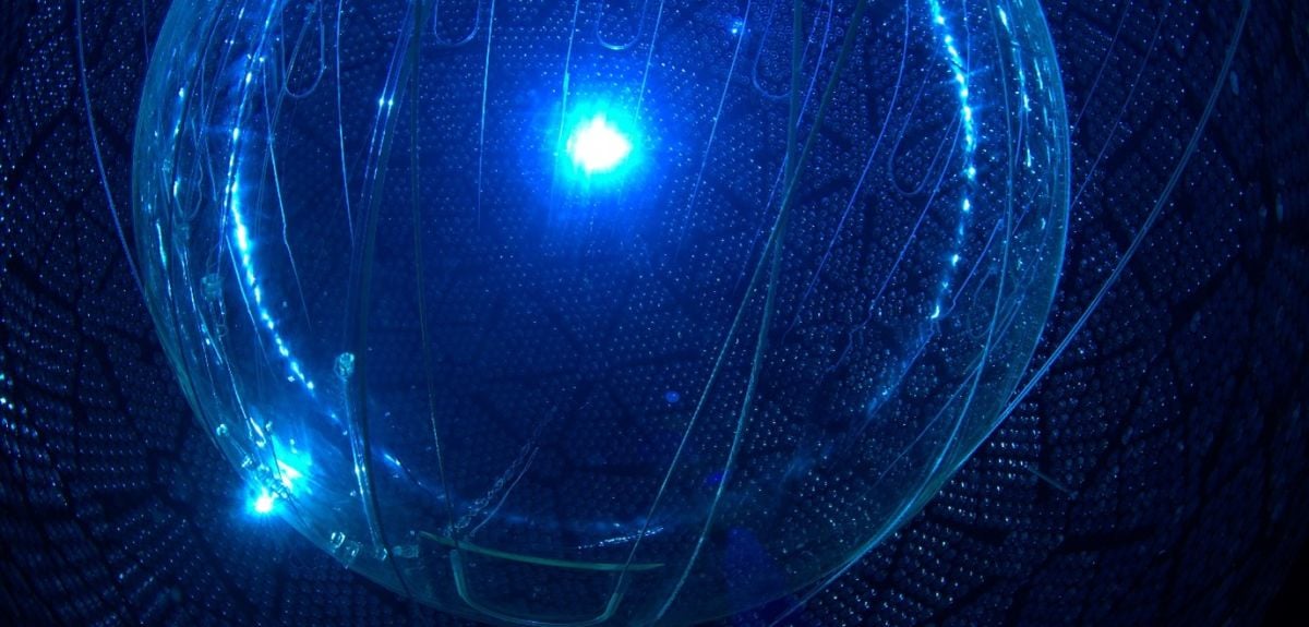 A round chamber with walls made up of photomultiplier tubes, illuminated by a central blue light.